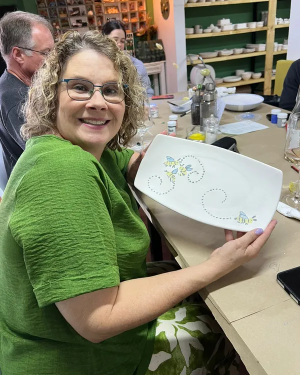 A customer holding a white platter painted with bees and dotted swirls